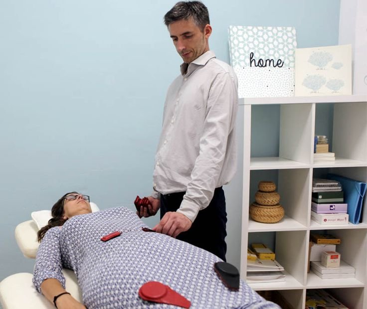 Terapeuta poniendo imanes a paciente en camilla biomagnetismo